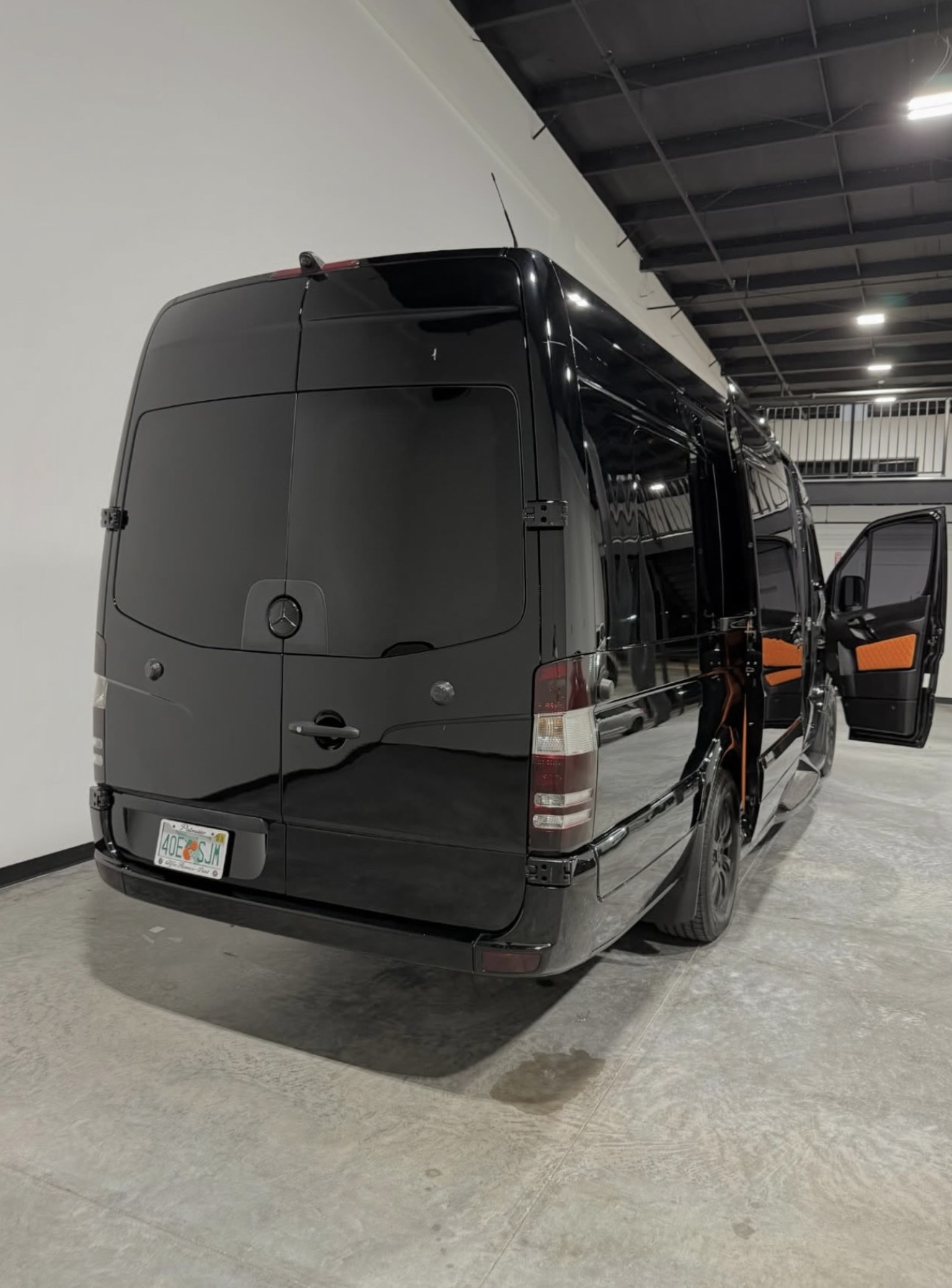 Matte black Mercedes Sprinter at a private jet hangar